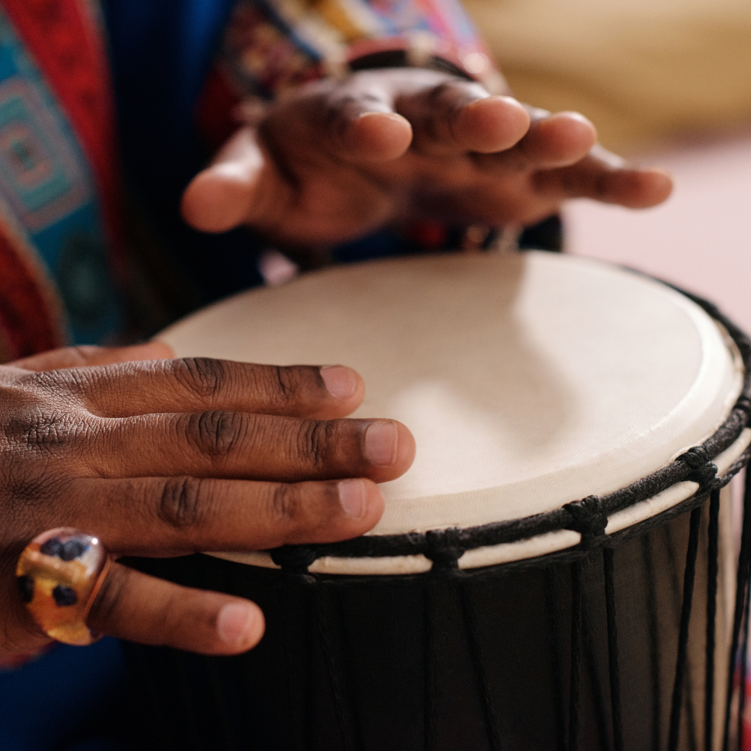 close up of hands playing a traditional african drum